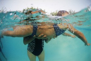 Woman Teaching Little Girl to Swim in Swimming Pool