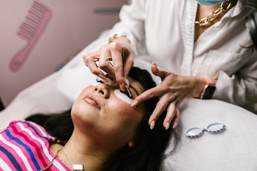 Free A woman receiving an eyelash application in a professional beauty salon setting. Detailed hands at work. Stock Photo